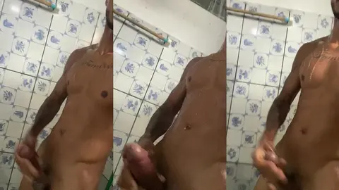 Mec tatoué se caresse contre le carrelage de la salle de bain