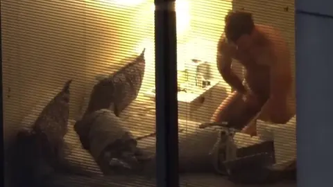 Un twink nu se penche dans une chambre baignée de lumière