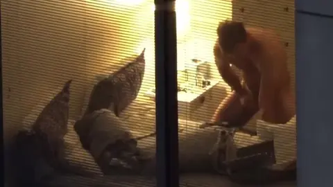 Un twink nu se penche dans une chambre baignée de lumière
