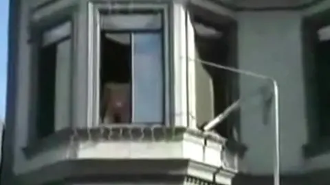 Homme Nu Repéré à la Fenêtre pendant une Fête de Rue