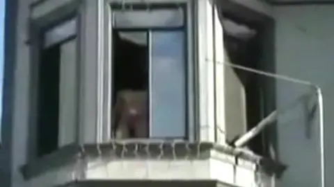 Homme Nu Repéré à la Fenêtre pendant une Fête de Rue