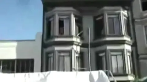 Homme Nu Repéré à la Fenêtre pendant une Fête de Rue