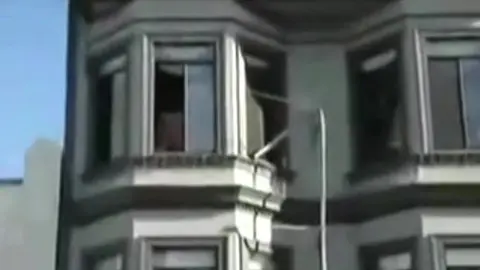 Homme Nu Repéré à la Fenêtre pendant une Fête de Rue